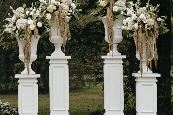 White architectural pillars in 3-foot and 4-foot heights topped with floral urns for a wedding ceremony