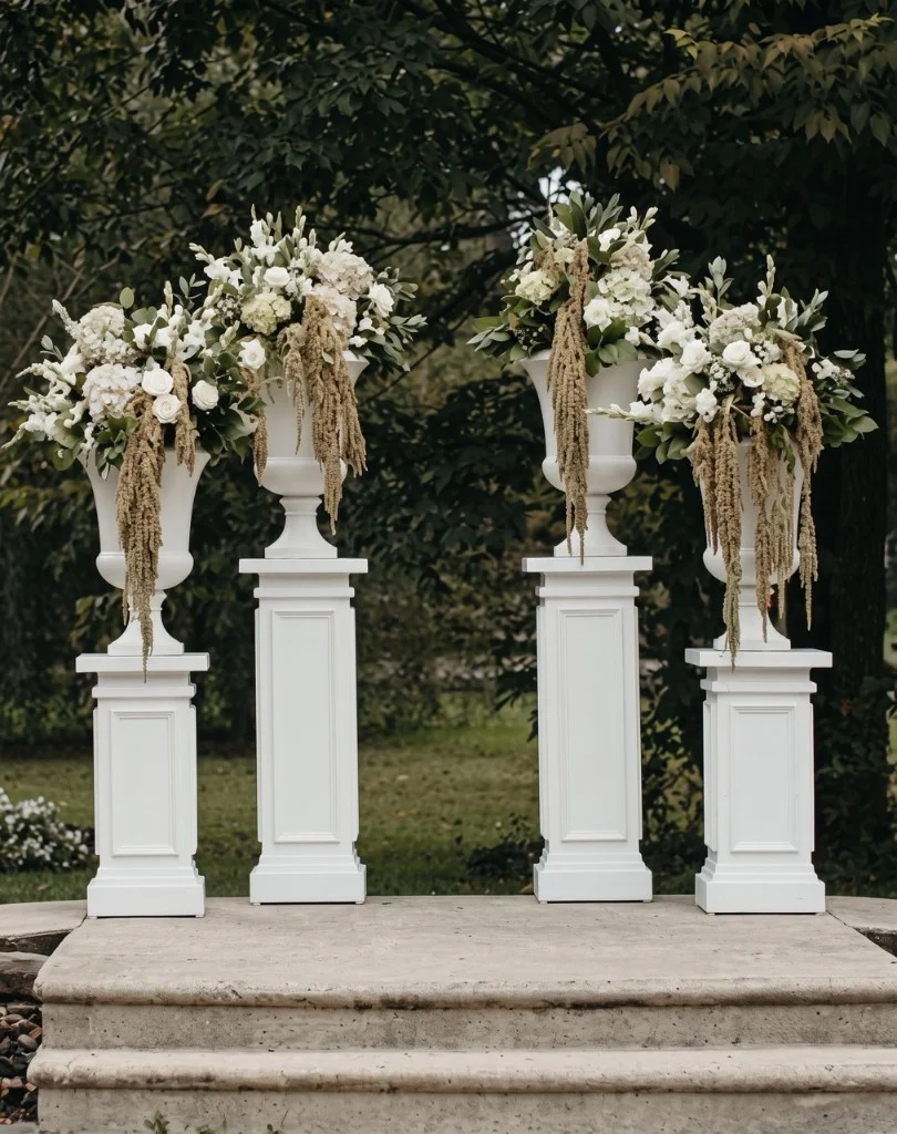 White architectural pillars in 3-foot and 4-foot heights topped with floral urns for a wedding ceremony