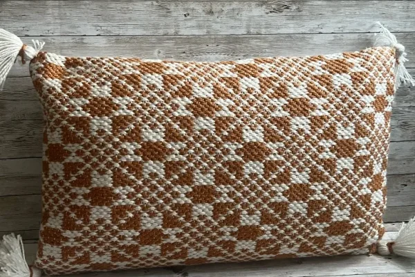 Rust and ivory woven lumbar rental pillow with tassels