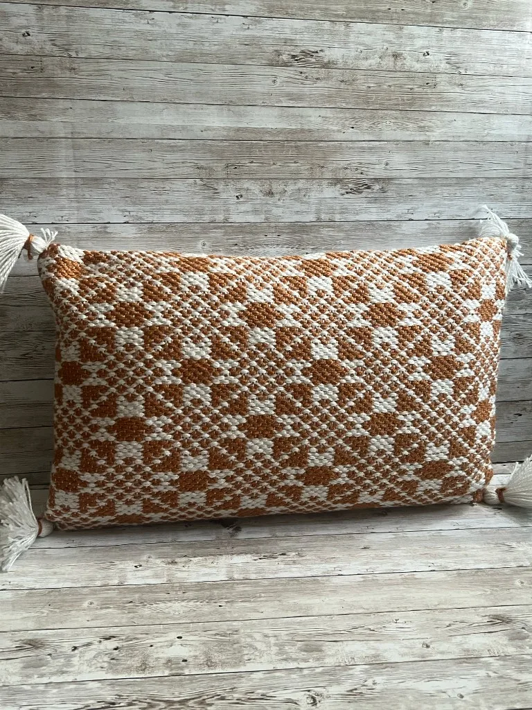 Rust and ivory woven lumbar rental pillow with tassels